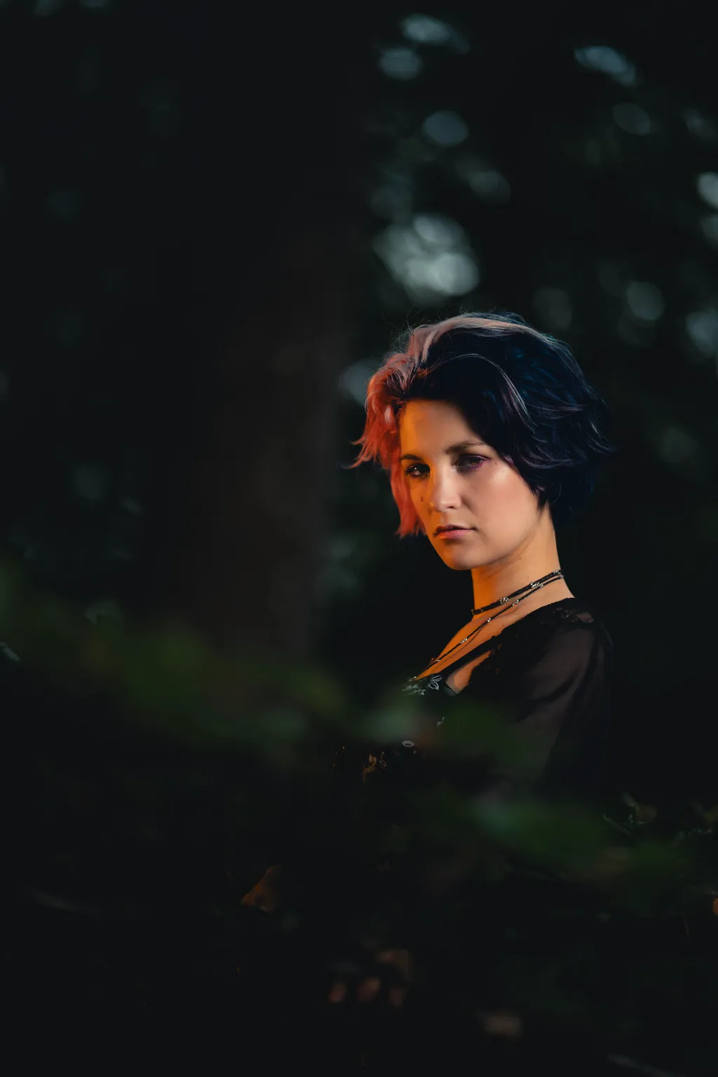 Editorial forest portrait of a woman with pink-tinted hair turning to camera in Luxembourg woods