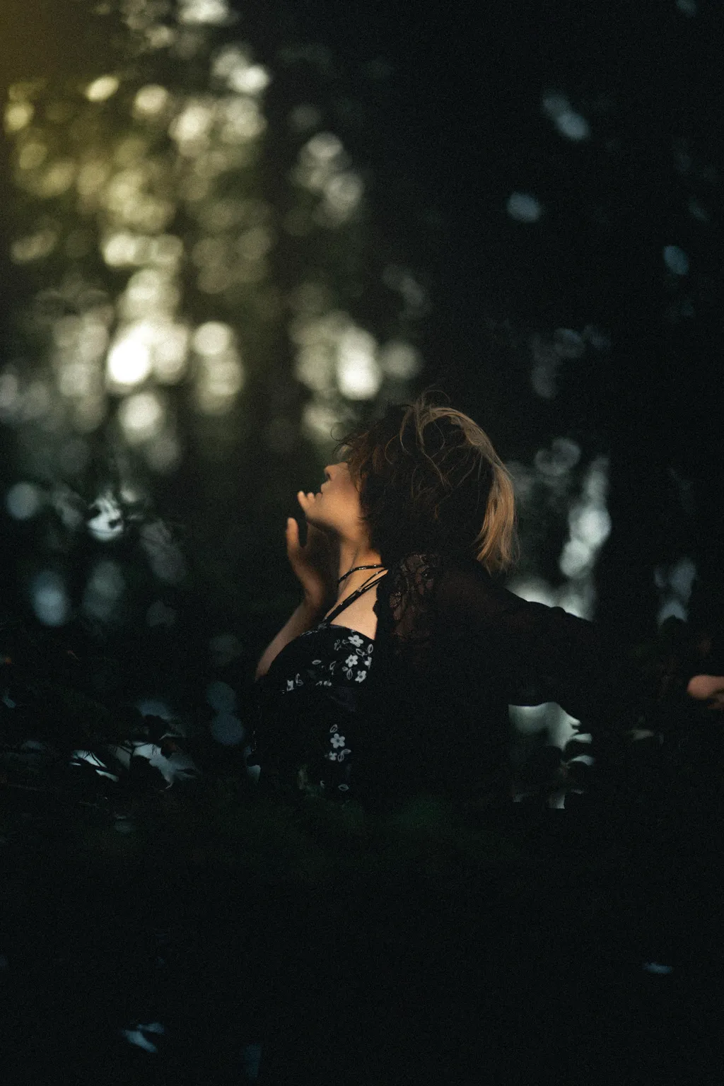 Profile of a woman looking up through forest bokeh in a cinematic Luxembourg outdoor portrait