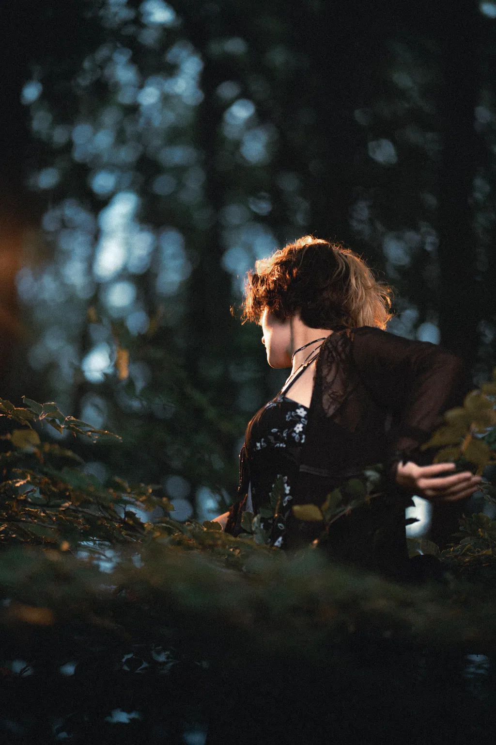 Woman in black lace seen from behind among forest leaves in a Luxembourg woodland portrait