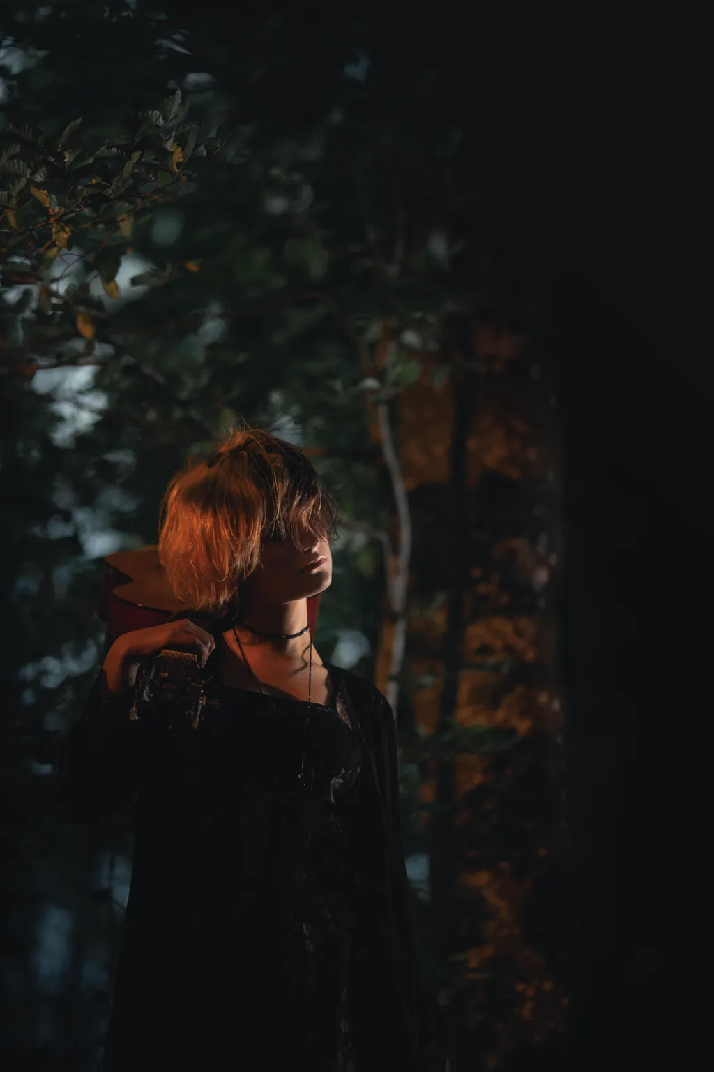 Woman lifting a camera by a tree, framed by foliage in a Luxembourg outdoor portrait