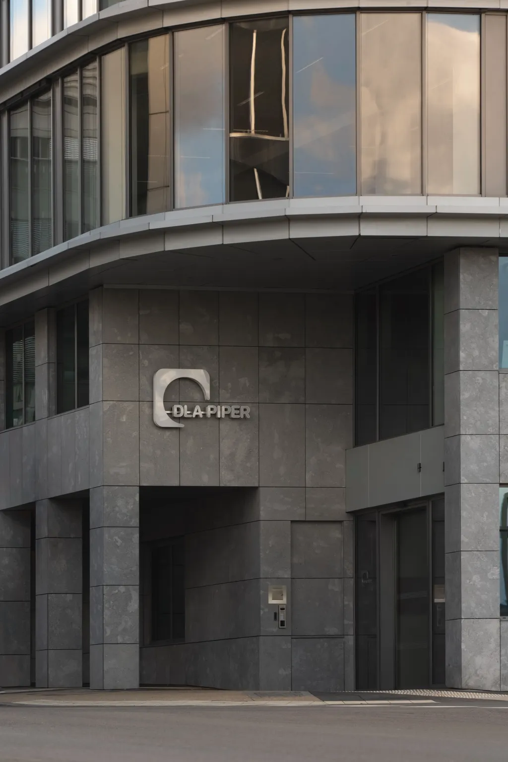 Close-up of the DLA Piper logo on the grey stone facade of the firm's Luxembourg office building
