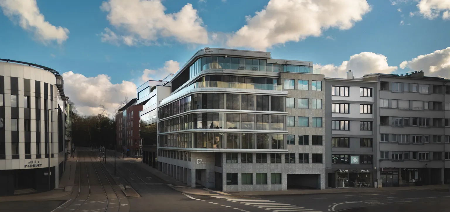 Corporate building photography of DLA Piper's rounded glass facade on a Luxembourg street corner