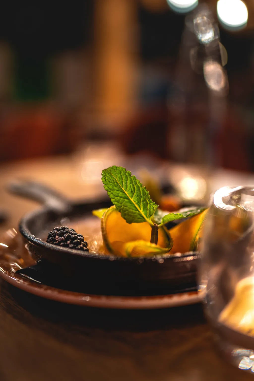 Close-up of a plated dessert with mint and blackberry, soft restaurant bokeh, food photography Luxembourg