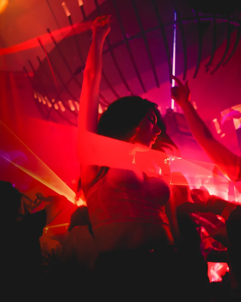 Crowd dancing with raised arms in a red-lit Luxembourg club, energy captured for social media video production