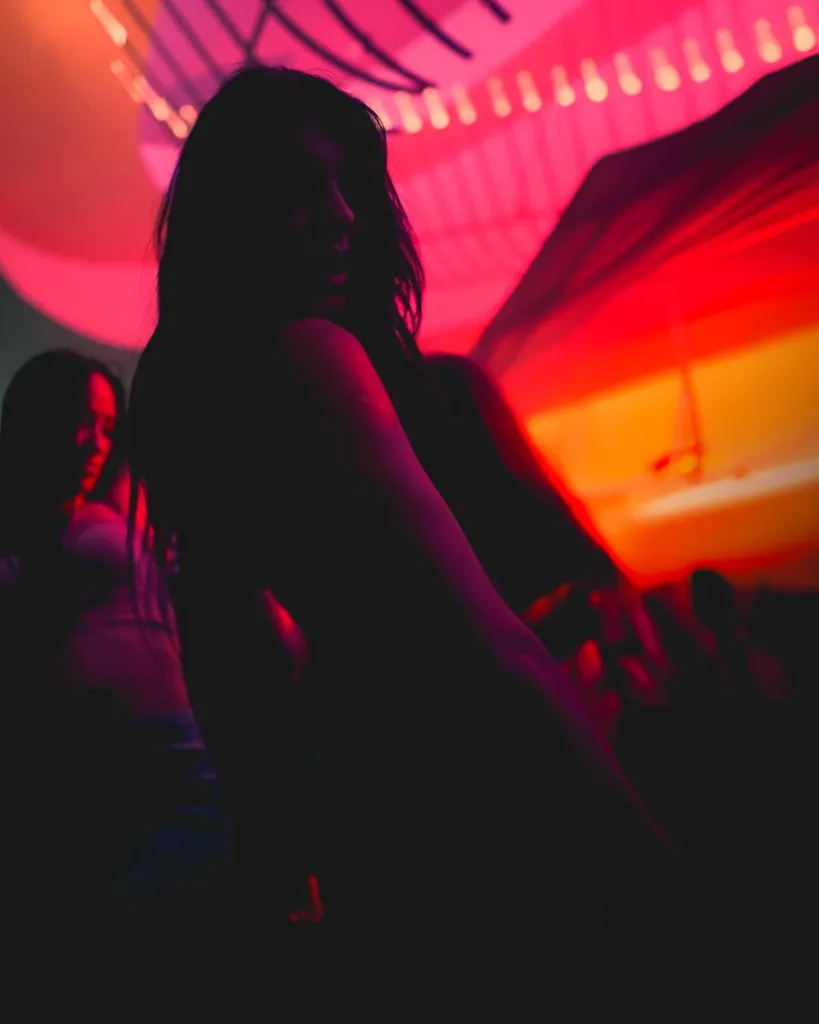 Silhouette of a dancer against red and orange club lights, moody night-out frame for Instagram and TikTok content