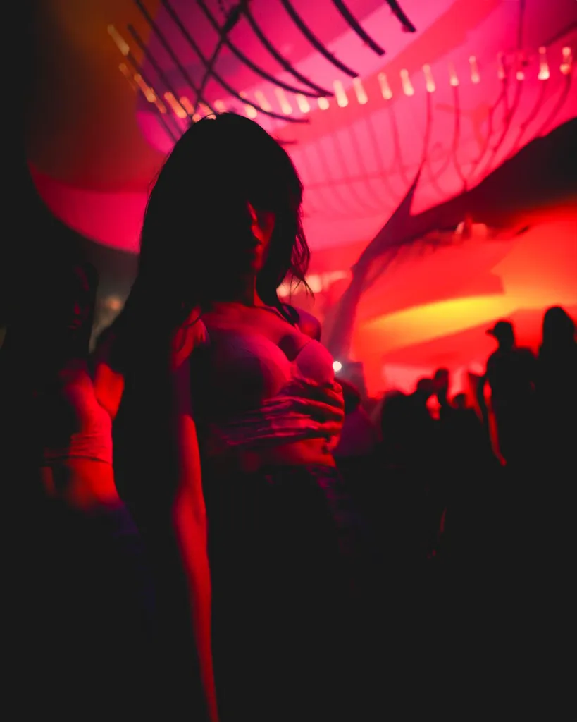 Backlit dancer in a glowing red Luxembourg nightclub with crowd behind, short-form social video aesthetic