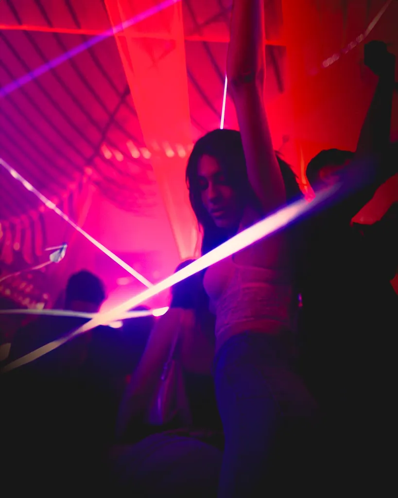 Dancer cutting through blue laser beams in a red-lit club, dynamic Luxembourg social media video production still