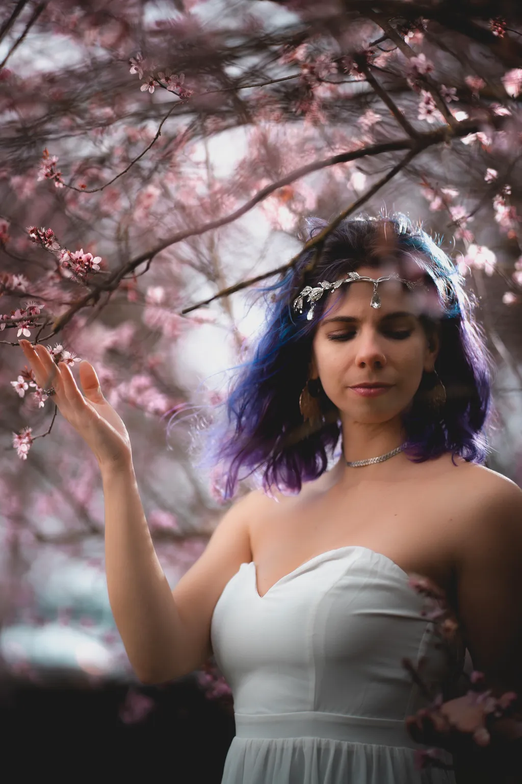 Full-length spring portrait of a woman in a strapless grey gown touching cherry blossoms in Luxembourg