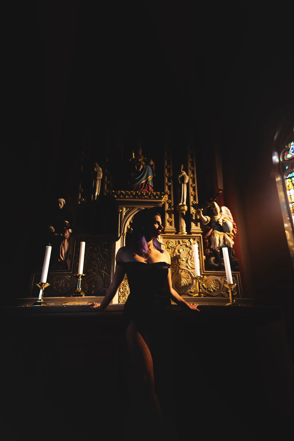 Fine-art portrait of a woman in a black gown by candlelight at a gilded altar in a Luxembourg church